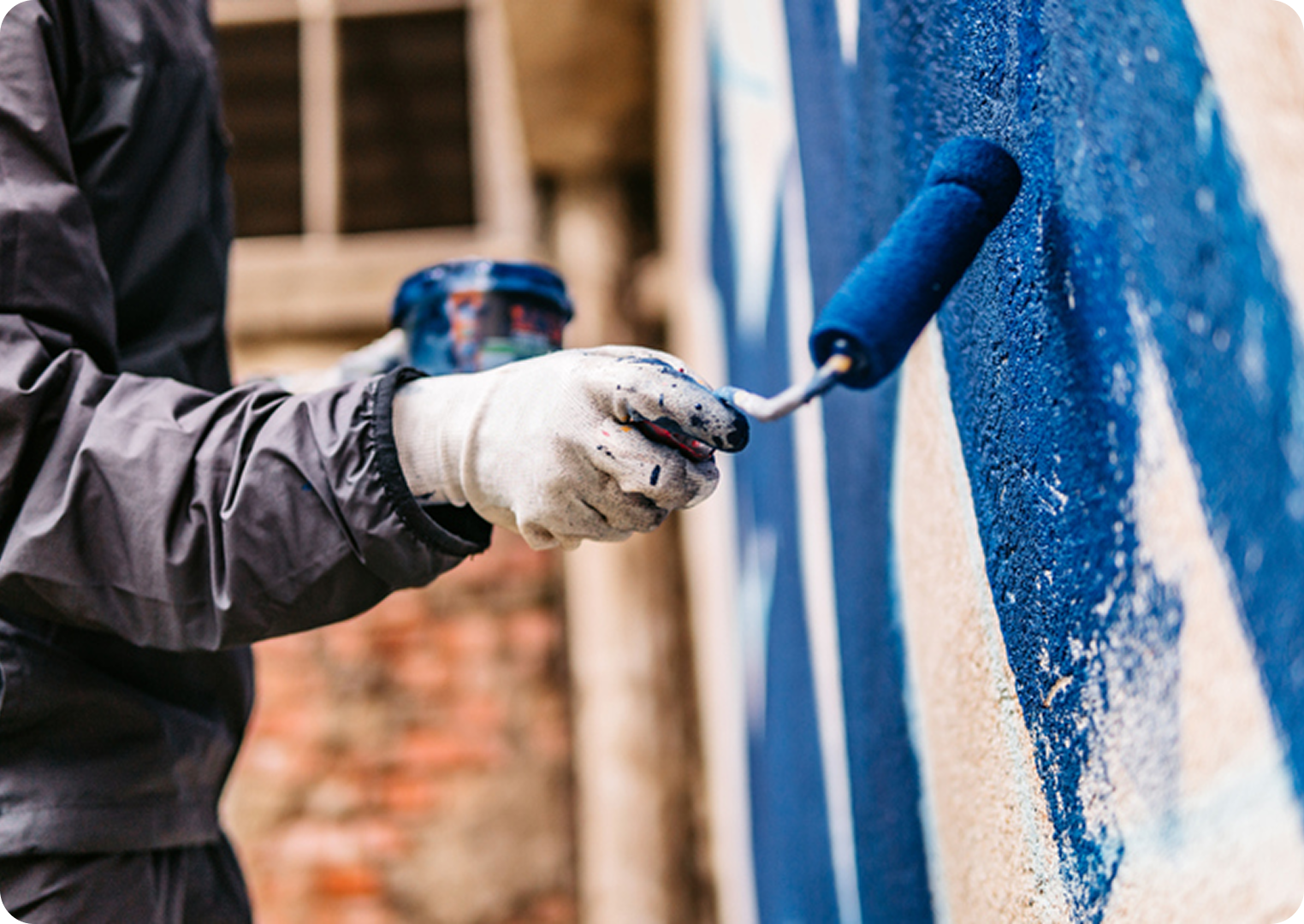 Person painting wall with blue roller.
