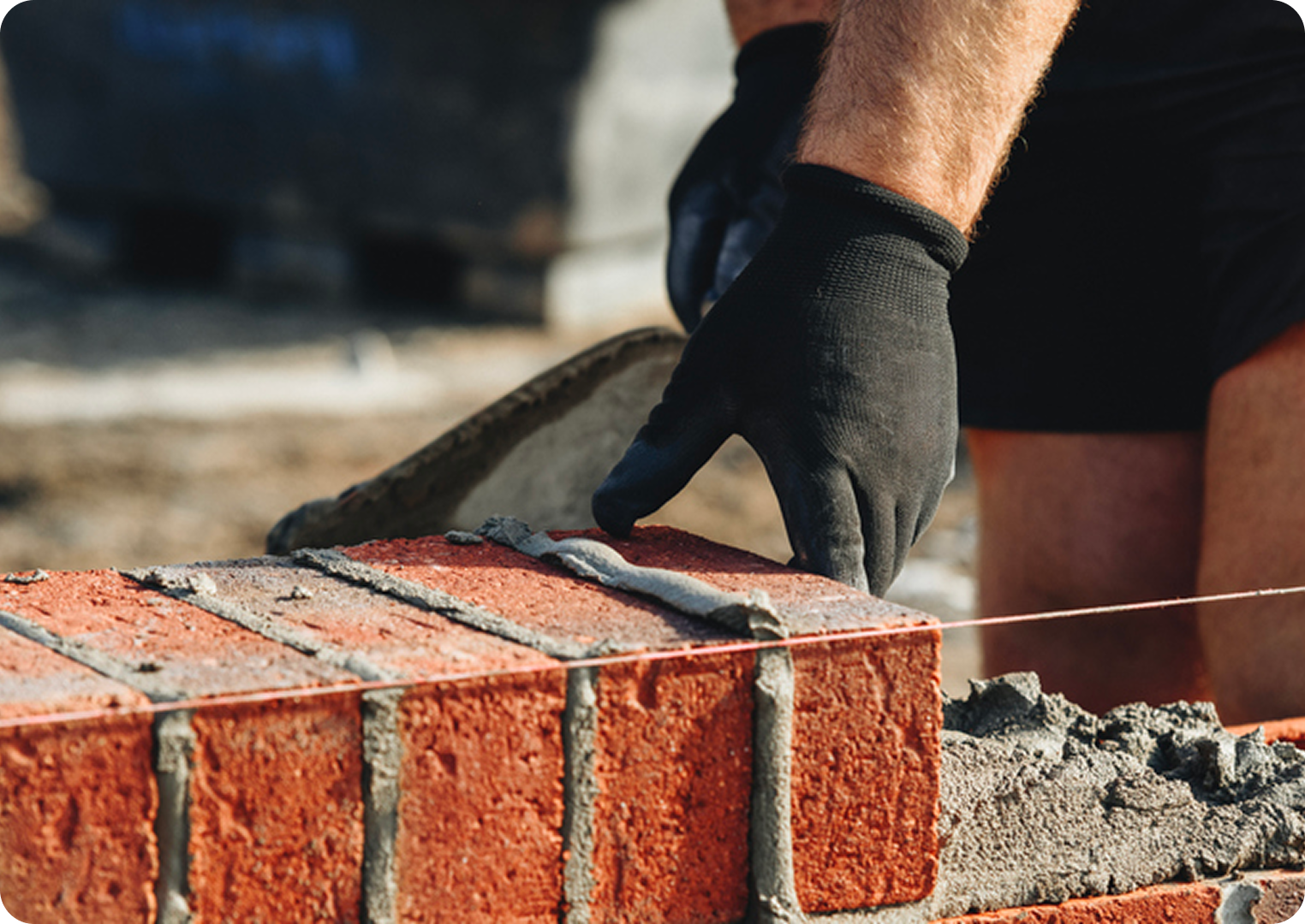 Bricklayer applying mortar on red bricks.