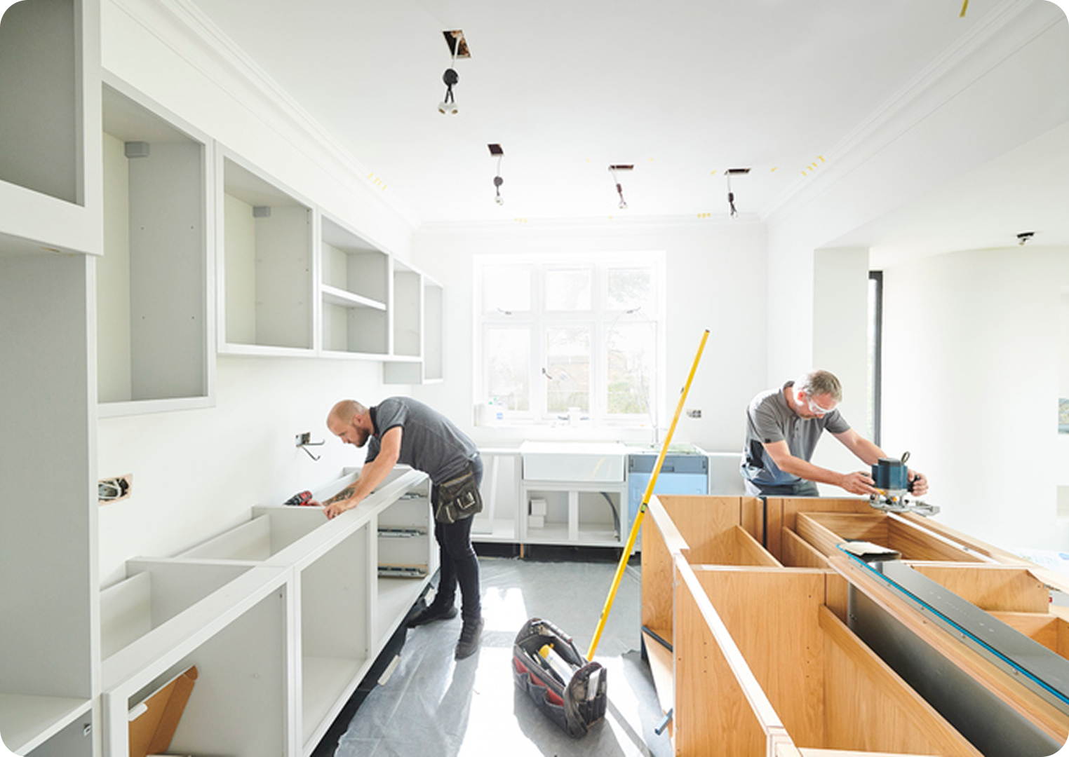 Workers installing cabinets in a bright kitchen.