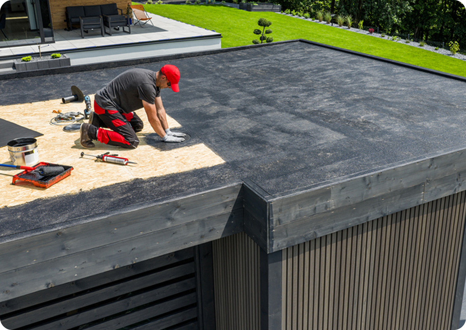 Worker installing roofing material on flat roof.