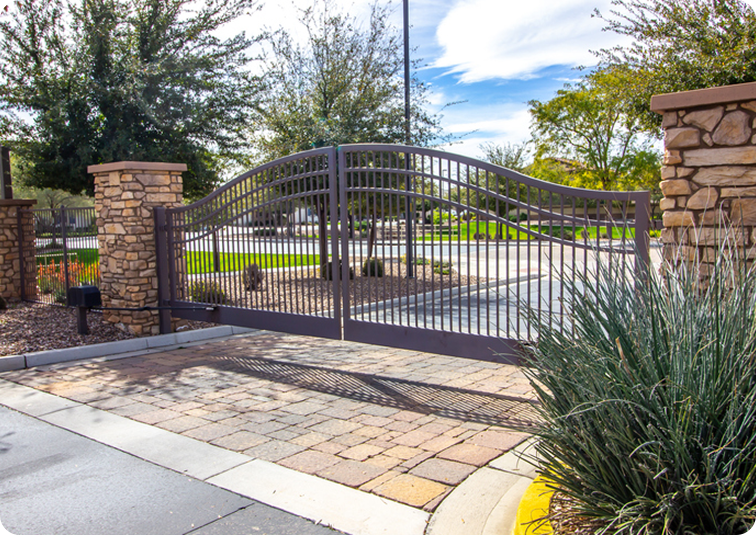 Wrought iron gate with stone pillars outdoors.