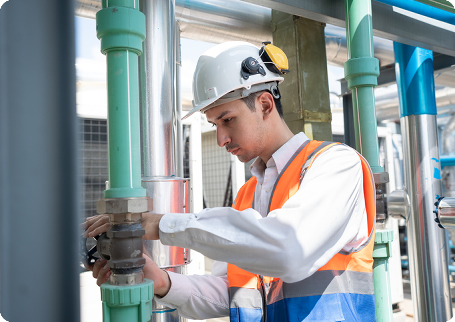 Engineer inspecting industrial pipes with tools.