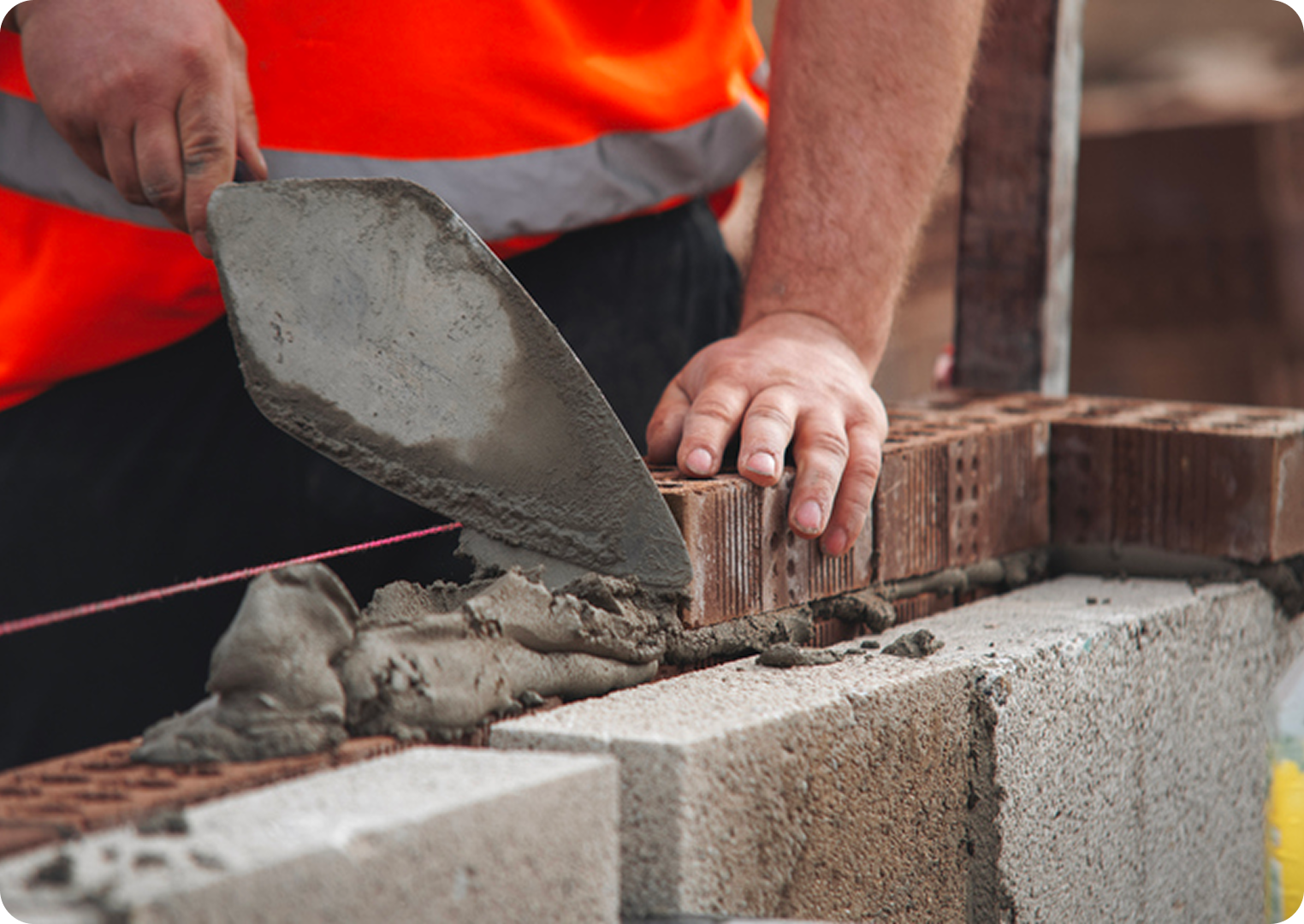 Builder laying bricks with a trowel.
