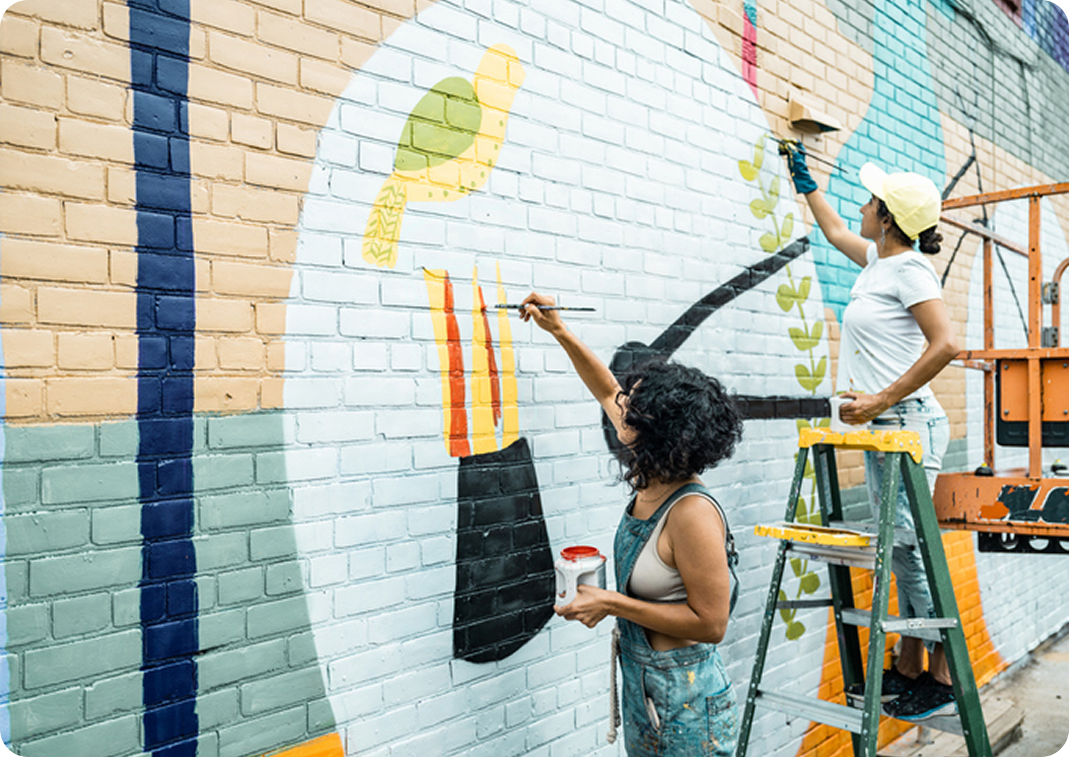 Artists painting a colorful mural on wall.
