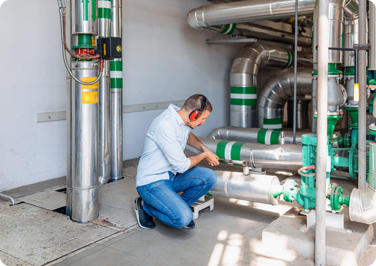 Technician inspecting industrial pipes and machinery.