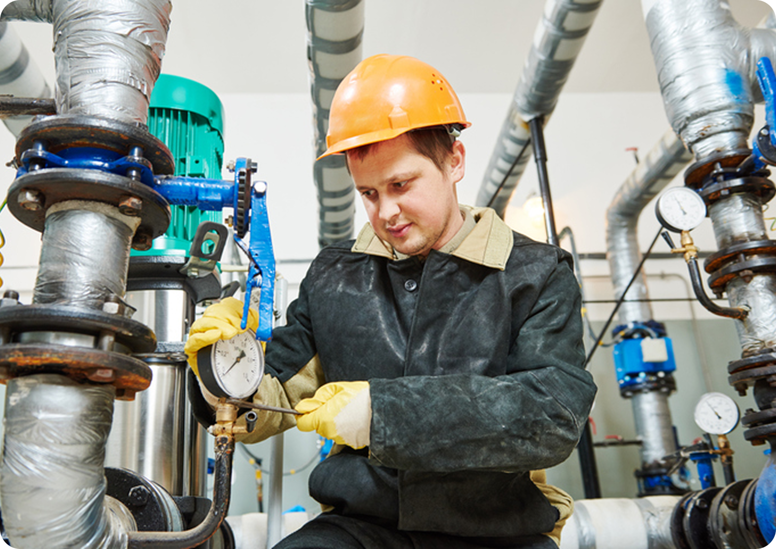 Worker adjusting pressure gauge in industrial setting.