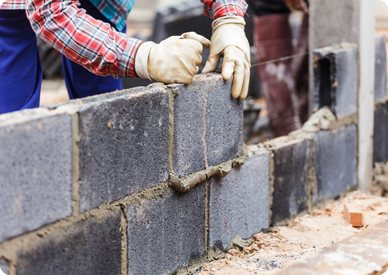 Worker building a wall with concrete blocks.