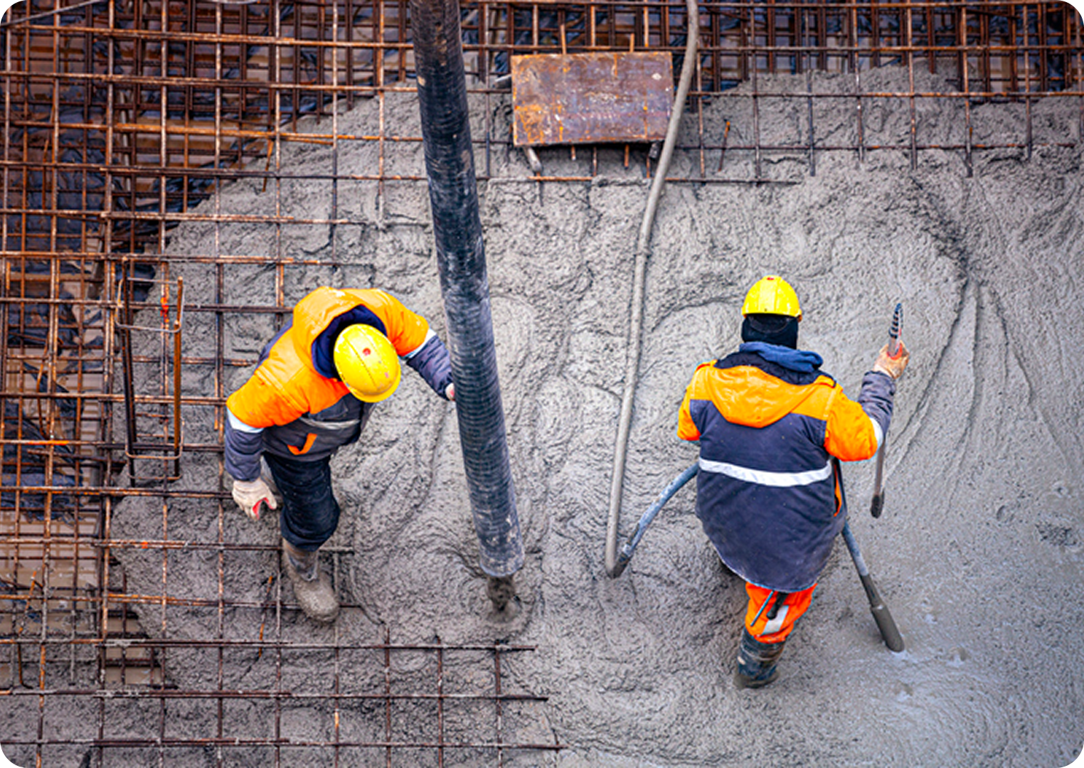 Construction workers pouring concrete at site.
