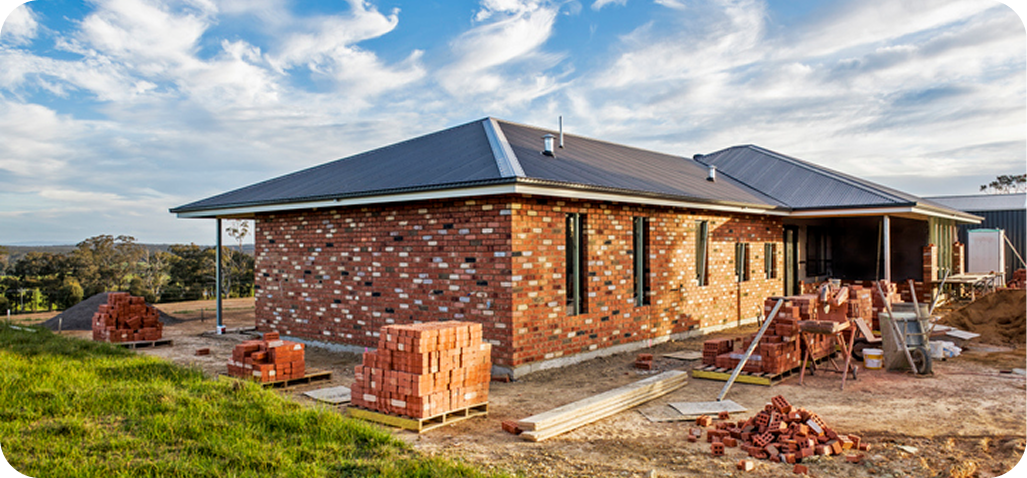 Brick house under construction with blue sky.