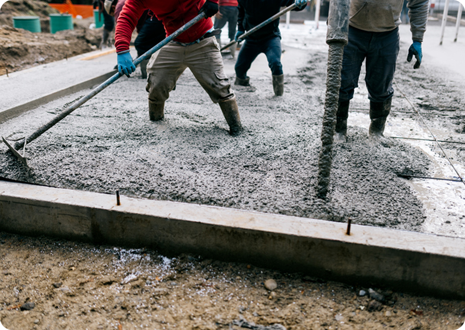 Workers pouring and leveling wet concrete foundation.