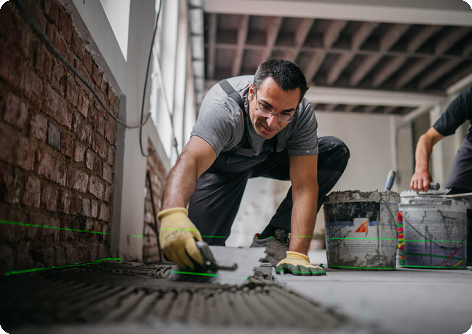 Worker tiling floor in construction site.